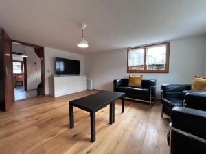 a living room with a table and a couch and a tv at Casa Biala Dimora - Ski IN/OUT in Vigens