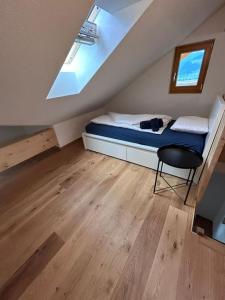 um quarto com uma cama e uma cadeira num sótão em Casa Biala Dimora - Ski IN/OUT em Vigens