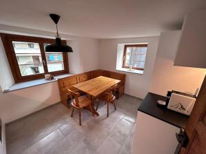 uma sala de jantar com uma mesa de madeira e 2 janelas em Casa Biala Dimora - Ski IN/OUT em Vigens