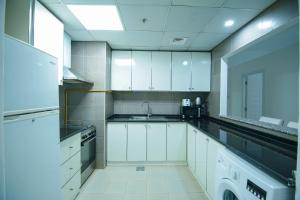 a kitchen with white cabinets and a sink at Home Away Holiday Homes in Dubai