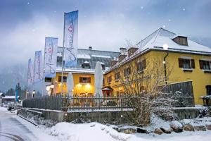 a yellow building with signs on it in the snow at DEVA Hotel Alpenglück in Weißbach