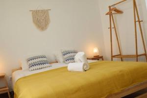Un dormitorio con una cama amarilla con toallas. en Casa Vento Budens en Budens