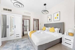 - une chambre avec un grand lit blanc et des oreillers jaunes dans l'établissement StoneTree - Furnished 1BR with Modern Design, à Dubaï