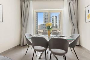 d'une salle à manger avec une table, des chaises et une fenêtre. dans l'établissement StoneTree - Furnished 1BR with Modern Design, à Dubaï