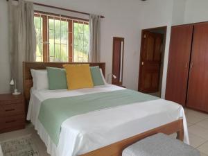 1 dormitorio con 1 cama grande con almohadas verdes y amarillas en Roz A Mer - Beach Apartment en Mahe