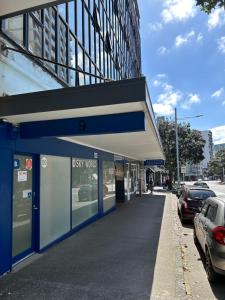een blauw-wit gebouw met auto's geparkeerd op een straat bij Sky World Cozy Home in Auckland