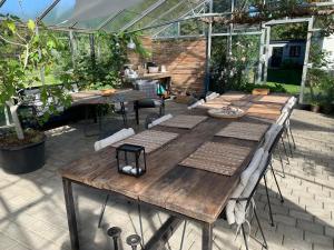 a long wooden table in a garden with a greenhouse at Mariegaardens Gæstehuse in Hillerød