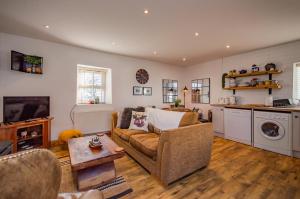 a living room with a couch and a kitchen at Cosy Farm Conversion In The Heart Of Pembrokeshire in Pembrokeshire