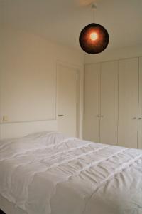 een slaapkamer met een wit bed en een licht bij Strandhuis 0102 in De Haan