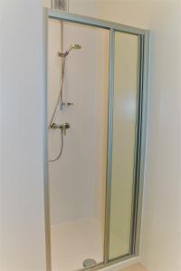 een douche met een glazen deur in de badkamer bij Strandhuis 0102 in De Haan