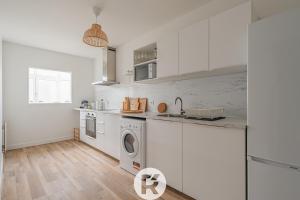 a kitchen with white cabinets and a washing machine at R 'AppartsT3 Serenity Haven in Torcy