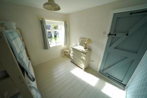 een slaapkamer met een deur, een dressoir en een raam bij Cranny Cottage Carnlough in Carnlough