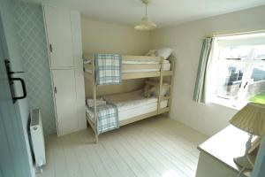 a small room with two bunk beds and a window at Cranny Cottage Carnlough in Carnlough