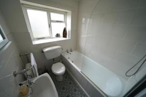 a bathroom with a tub and a toilet and a sink at Cranny Cottage Carnlough in Carnlough