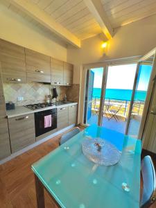 a kitchen with a blue table with a view of the ocean at TRAMONTO Suite-Rome Airport FCO-Fronte mare in Fiumicino