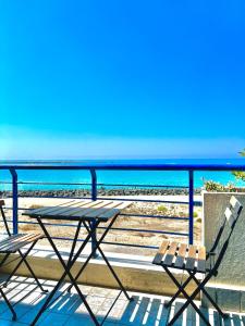 un tavolo e sedie su un balcone con vista sull'oceano di TRAMONTO Suite-Rome Airport FCO-Fronte mare a Fiumicino