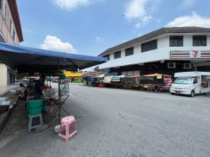 a person sitting at a stand on the side of a street at Green Space Homestay Cozy Family(8-12pax) in Ipoh