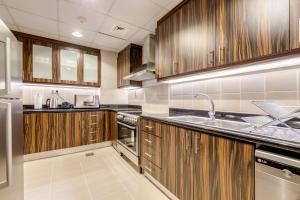 een grote keuken met houten kasten en een wastafel bij GLOBALSTAY. Modern Apartments steps to JBR Beach in Dubai