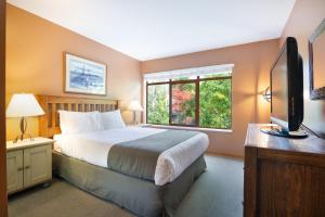 a bedroom with a bed and a tv and a window at Whistler Vacation Club at Twin Peaks in Whistler