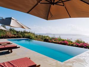 ein Pool mit Sonnenschirm und ein paar Blumen in der Unterkunft Karabai Villa in Matemwe