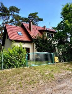 une maison avec un toit rouge et une clôture dans l'établissement Domek na Sosnowej, à Pobierowo