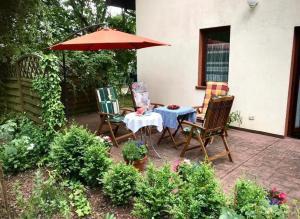une terrasse avec 2 chaises et une table avec un parasol dans l'établissement Domek na Sosnowej, à Pobierowo