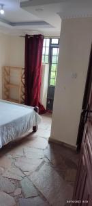 a bedroom with a bed in a room with a window at Hillbilly Bush Lodge in Kisumu