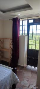 キスムにあるHillbilly Bush Lodgeのベッドルーム1室(ベッド1台付)、窓付きのドアが備わります。