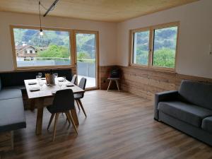 sala de estar con mesa, sofá y ventanas en Montepart Zillertal en Hainzenberg