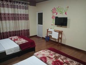 Zimmer mit 2 Betten und einem Flachbild-TV in der Unterkunft Thuvaraga Inn in Nuwara Eliya