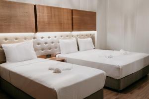 two beds in a hotel room with white sheets at Ceneviz Suit Hotel in Akçakoca