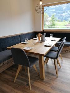 a wooden table with chairs and a large window at Montepart Zillertal in Hainzenberg