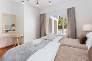 a white bedroom with two beds and a window at Q on Westford in Cape Town