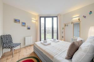 a bedroom with a bed and a chair and a window at Nids de Loire in Tours