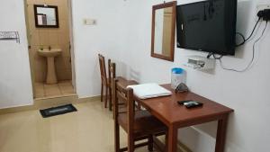 a room with a table and a television on a wall at CATCH A WAVE BUDGET STAY in Mahabalipuram