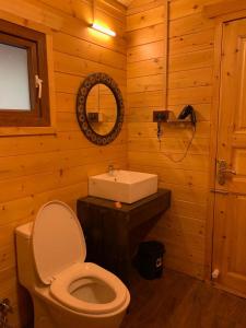 a wooden bathroom with a toilet and a sink at Maruti Villa in Kodaikānāl