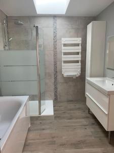 a bathroom with a shower and a tub and a sink at L havre de paix in Avelin