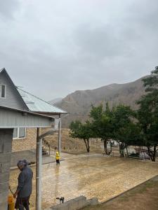 Un uomo in piedi fuori da una casa sotto la pioggia di Jyrgal jashoo guest house 