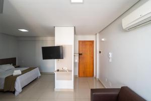 a bedroom with a bed and a flat screen tv at Onix Bueno Residence - ONX in Goiânia
