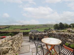 a patio with a table and chairs and a stone wall at 2 Ty Capel in Corwen
