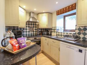 a kitchen with wooden cabinets and a counter top at 2 Ty Capel in Corwen