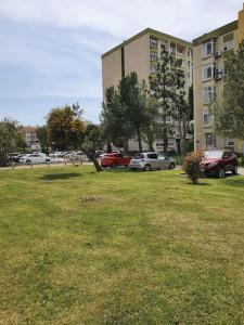 ein Grasfeld mit Autos, die vor einem Gebäude geparkt sind in der Unterkunft Bostanlı Sahile Yakın 2+1 Daire in Karşıyaka