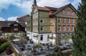 - un grand bâtiment avec une terrasse en face dans l'établissement Appenzeller Huus Löwen, à Gonten