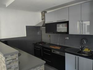 uma cozinha com armários brancos e um balcão preto em Kuća Barbara em Slavonski Brod