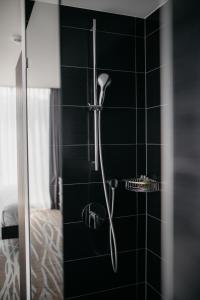 a shower in a bathroom with black tiles at IIP Apartments in Spreitenbach
