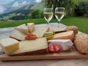 a plate of cheese and bread and two glasses of wine at Pitznerhof in Maranza
