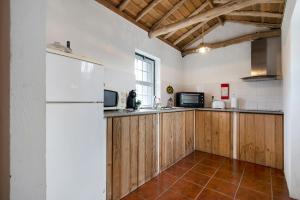 uma cozinha com armários de madeira e um frigorífico branco em Adega Maciel em Lajido