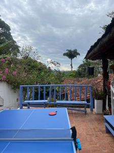 une table bleue et des bancs sur un patio dans l'établissement Tree of Life - Hostel, à Barichara