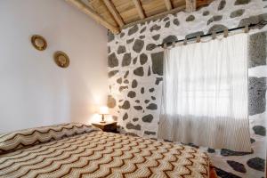 a bedroom with a bed and a rock wall at Adega Maciel in Lajido