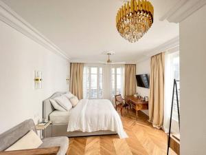 a white bedroom with a bed and a chandelier at Charmant Studio Palais Royal Musée du Louvre in Paris